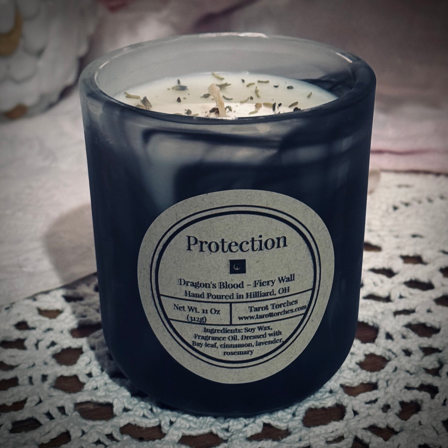 A soy wax candle with a black swirl vessel, with a label that reads "Protection".
