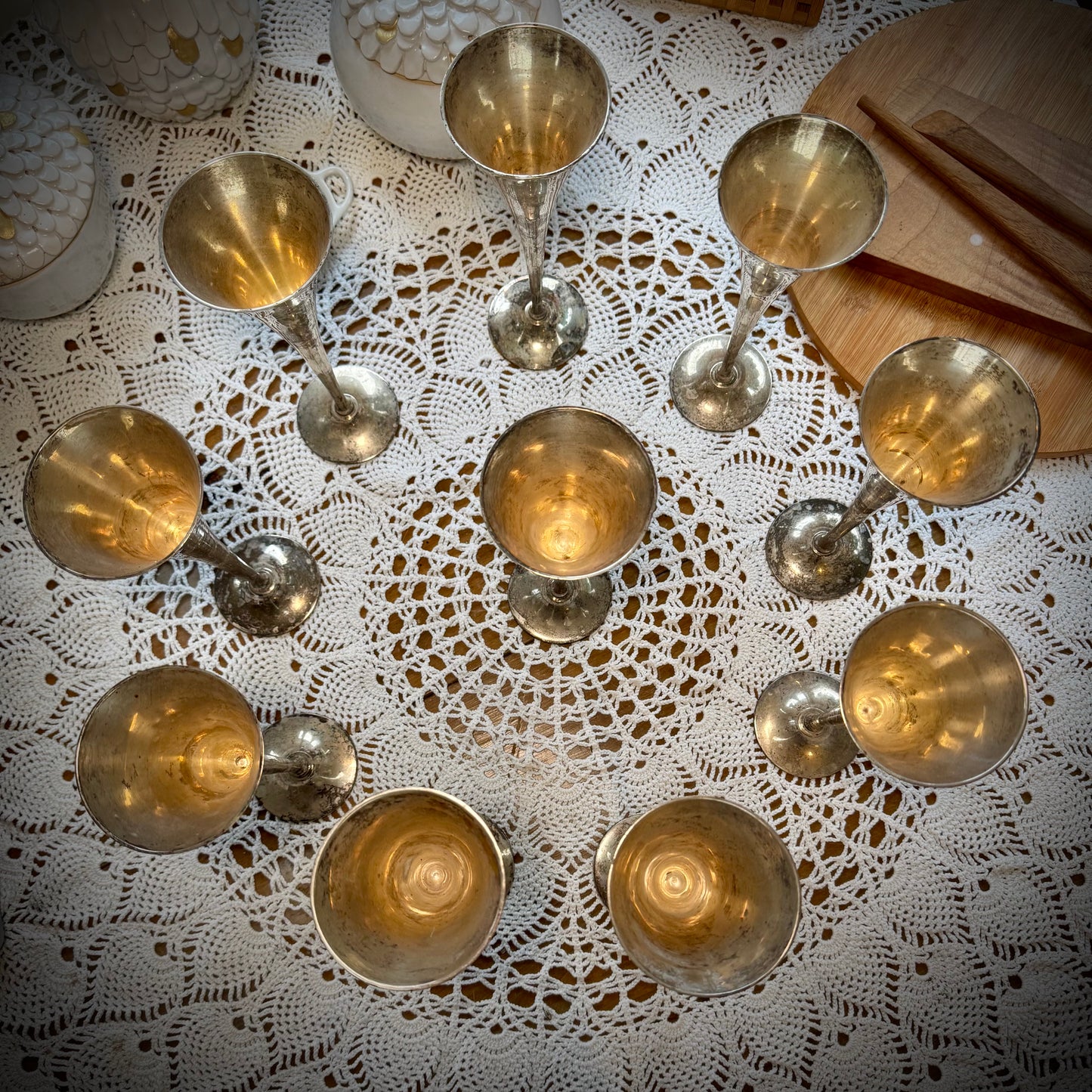 A set of vintage silver plate champagne flutes displayed on a table with a lace tablecloth.