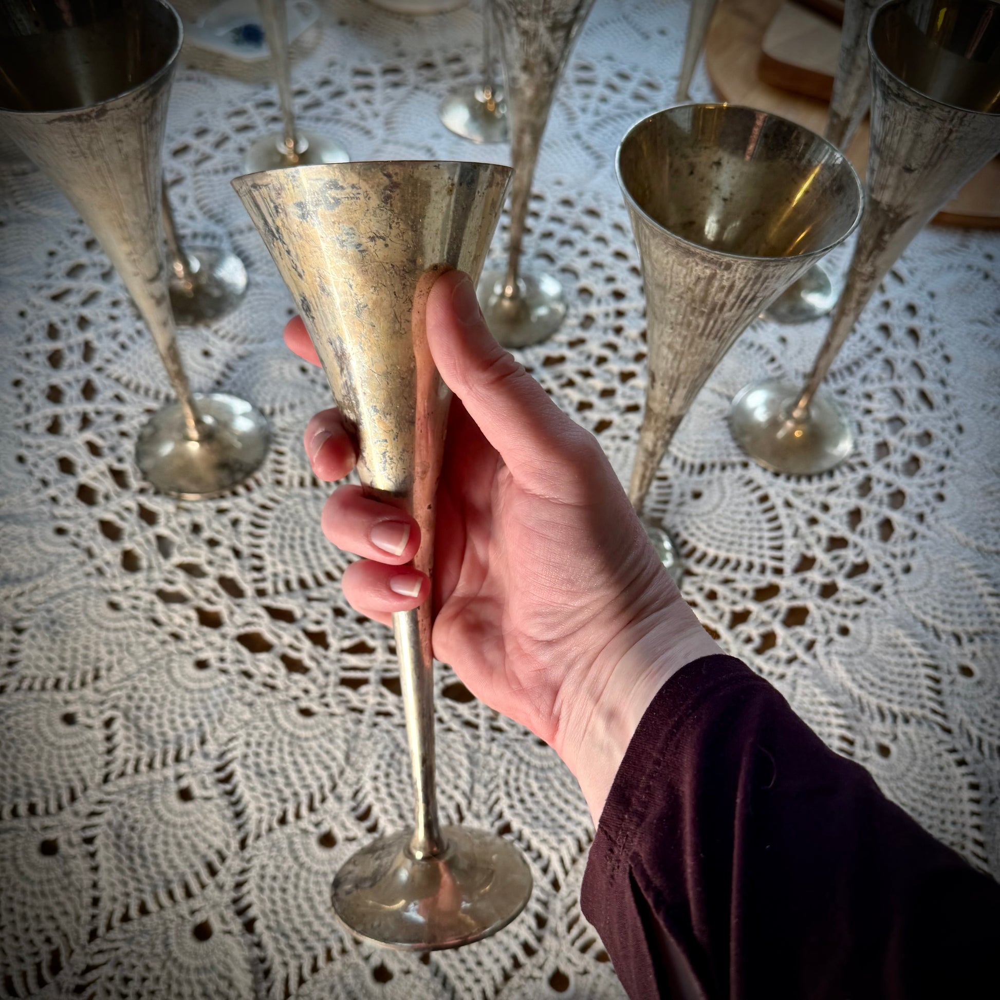 A set of vintage silver plate champagne flutes, one being held close to view