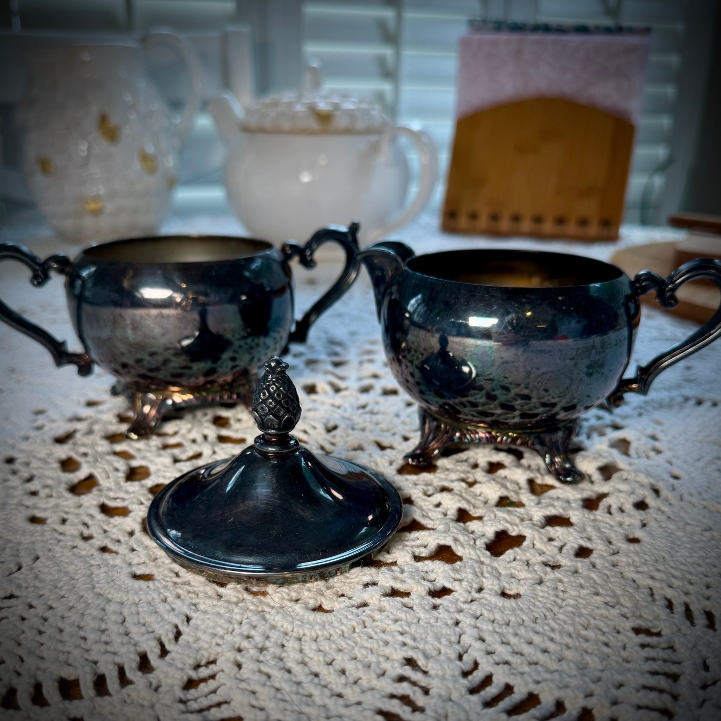 A vintage WM Rogers Silverplate cream and sugar set on a table with a lace tablecloth.