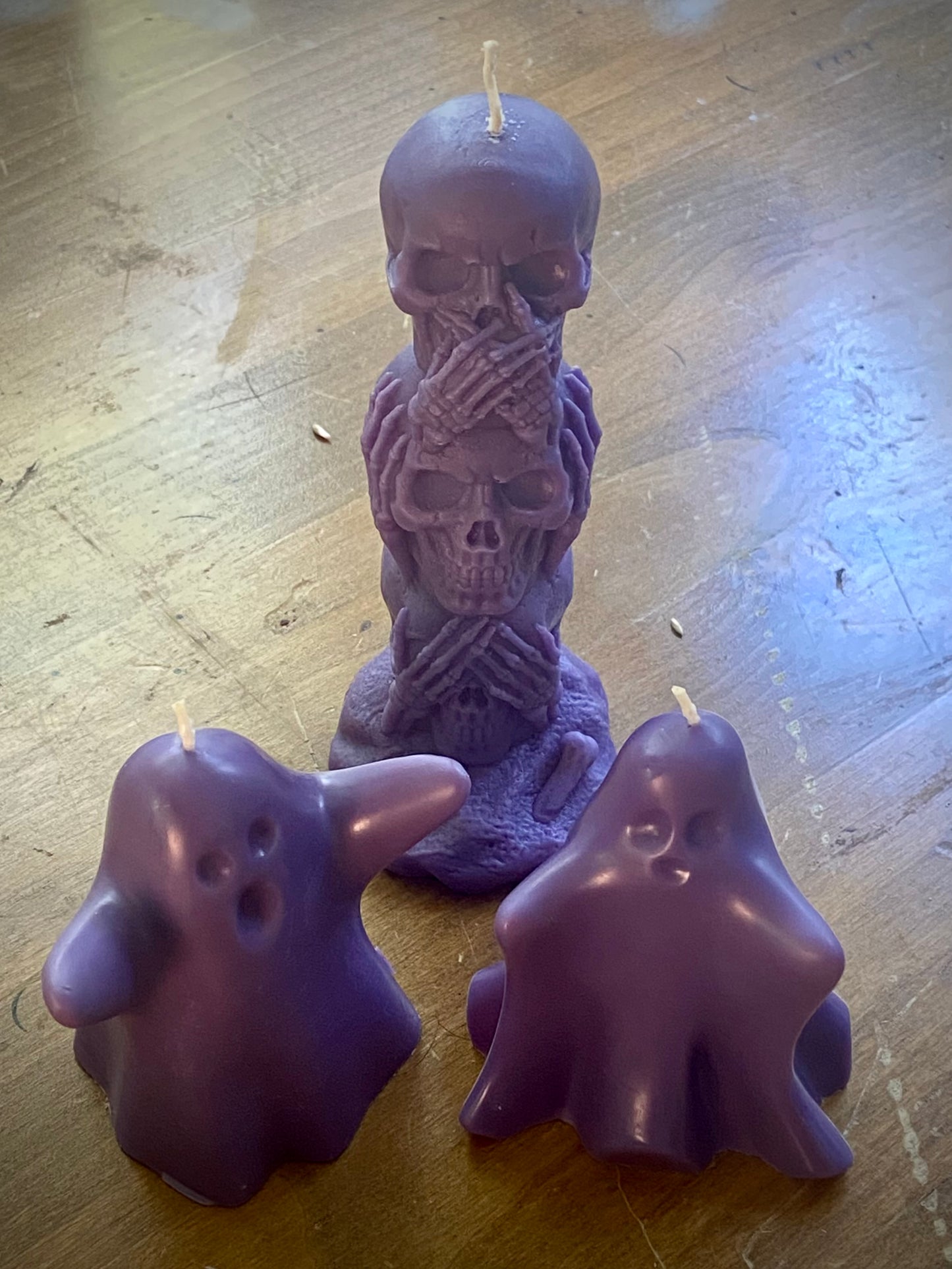 A set of molded purple Halloween candles including a stack of skulls and two ghosts.
