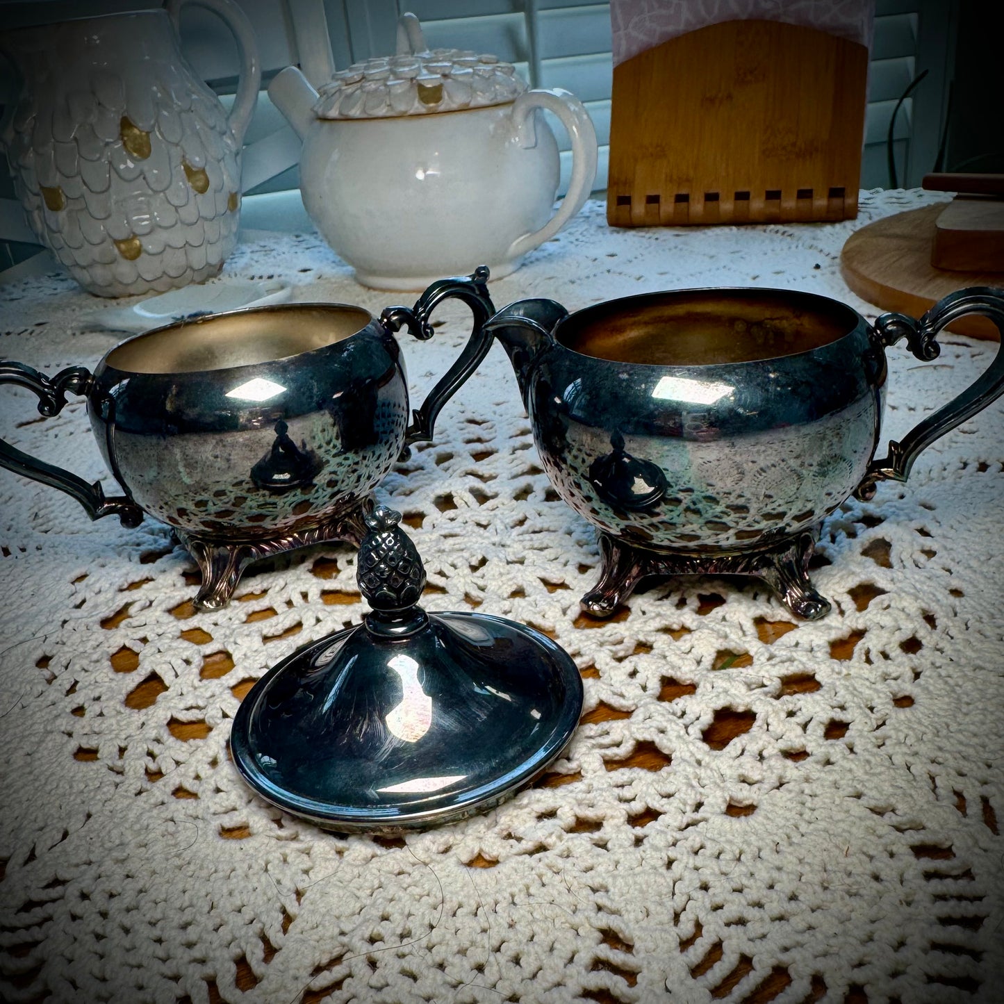 A vintage WM Rogers Silverplate cream and sugar set on a table with a lace tablecloth.