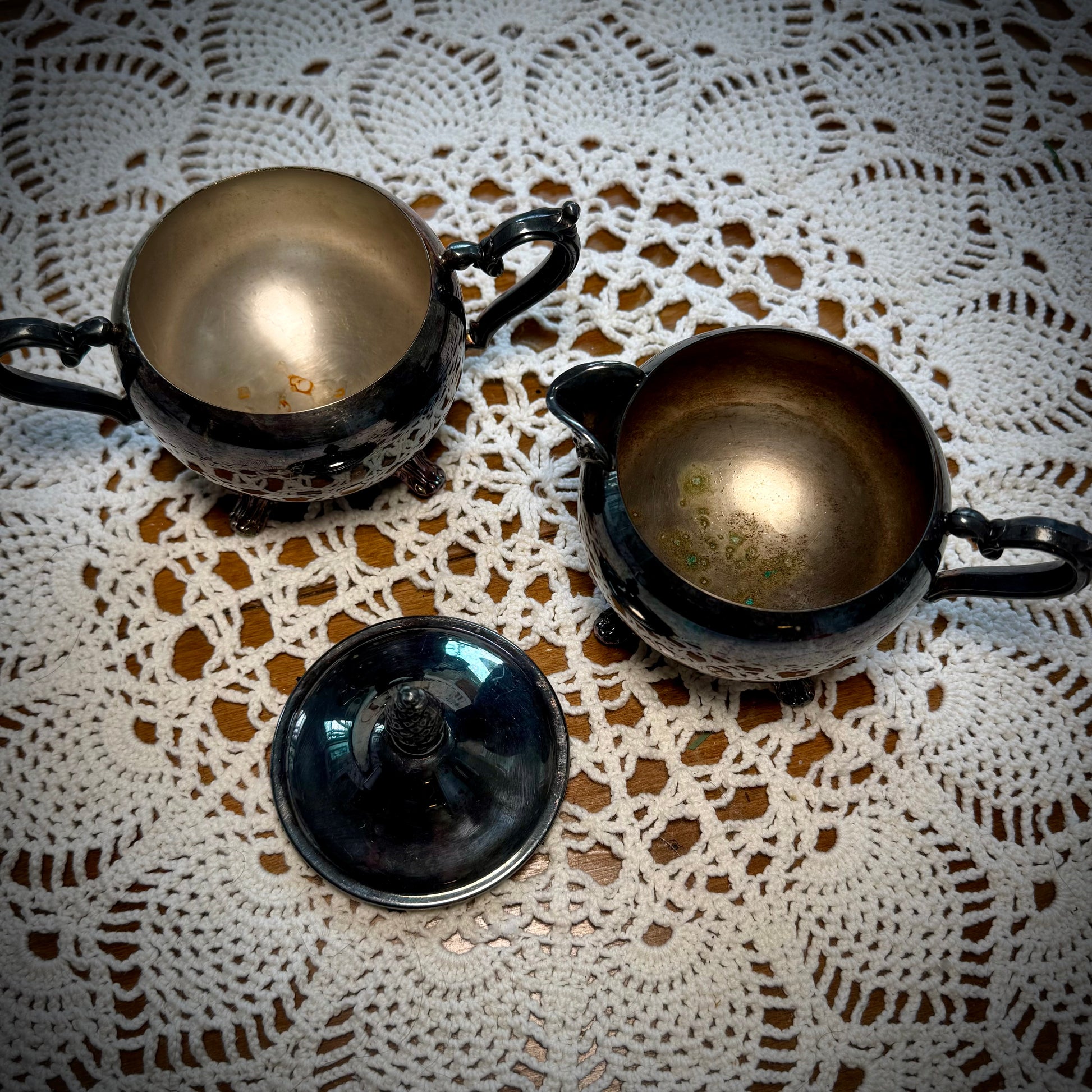 Aerial view of vintage WM Rogers Silverplate cream and sugar set on a table with a lace tablecloth.