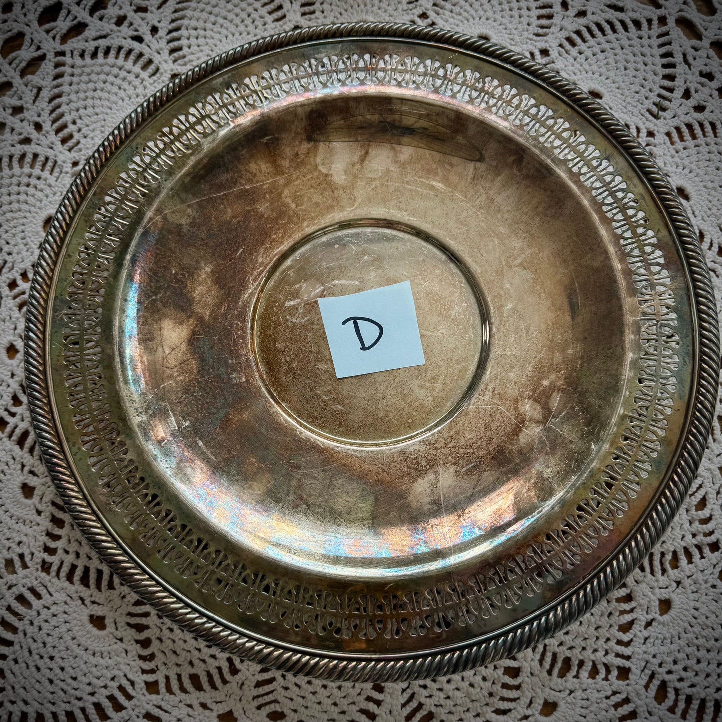 A silverplate round offering tray is displayed on a white lace surface. The tray has a post-it with the letter "D"