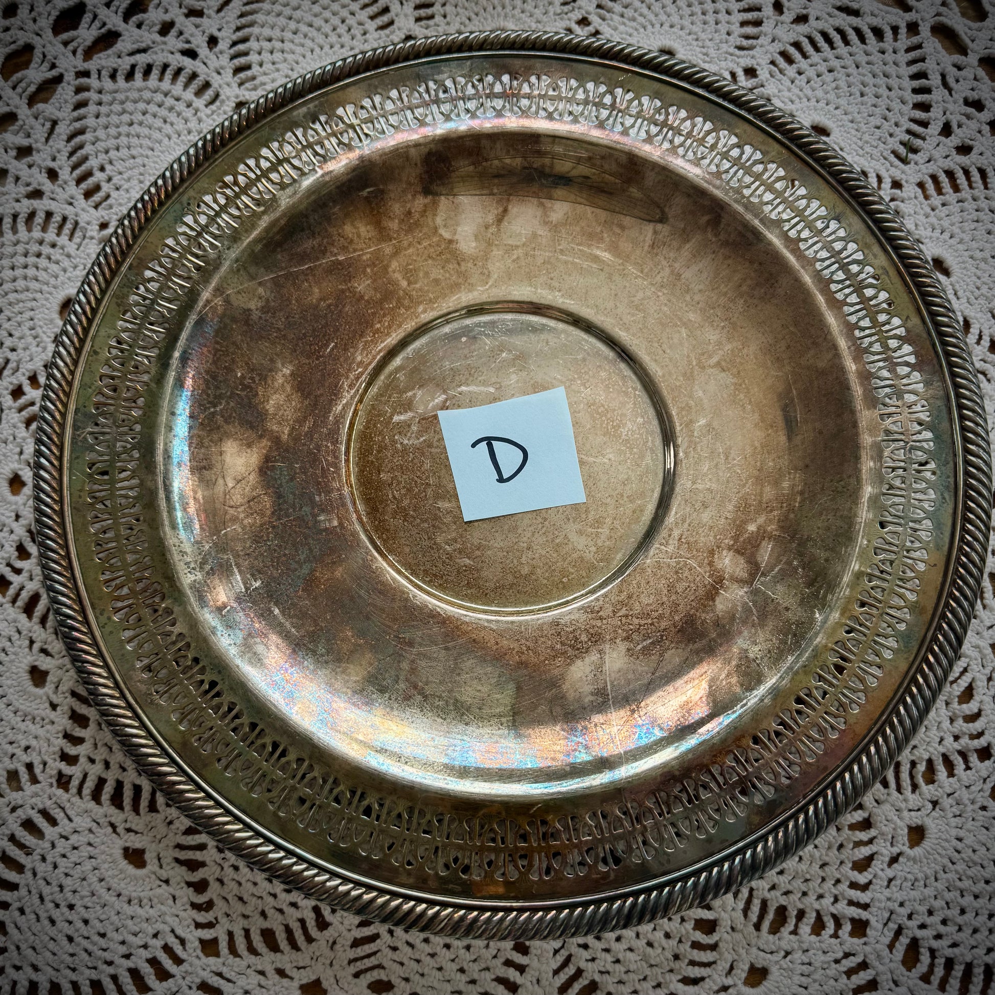 A silverplate round offering tray is displayed on a white lace surface. The tray has a post-it with the letter "D"