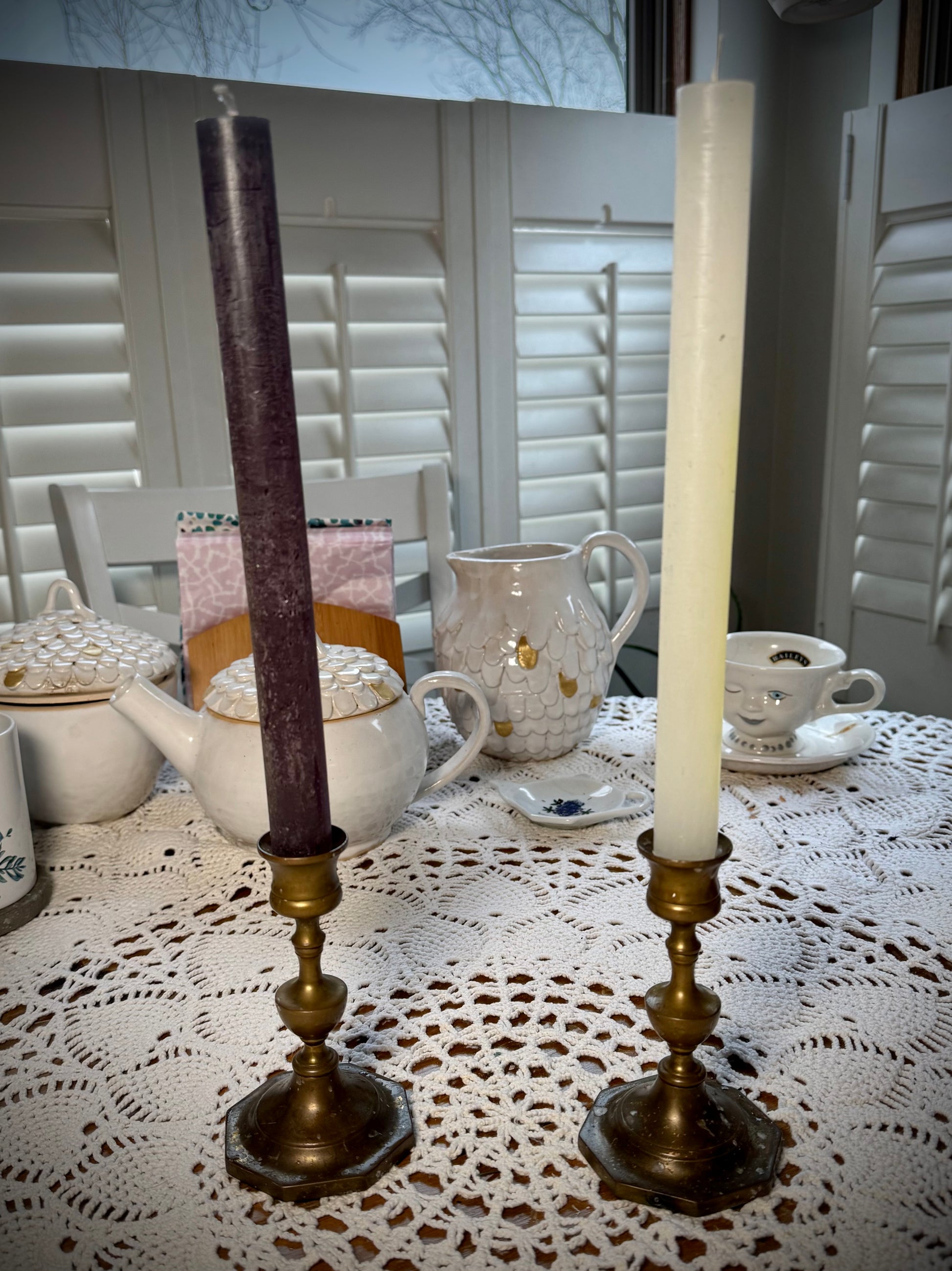 A pair of vintage brass candle holders with an octagonal base, each holding a different color taper candle.