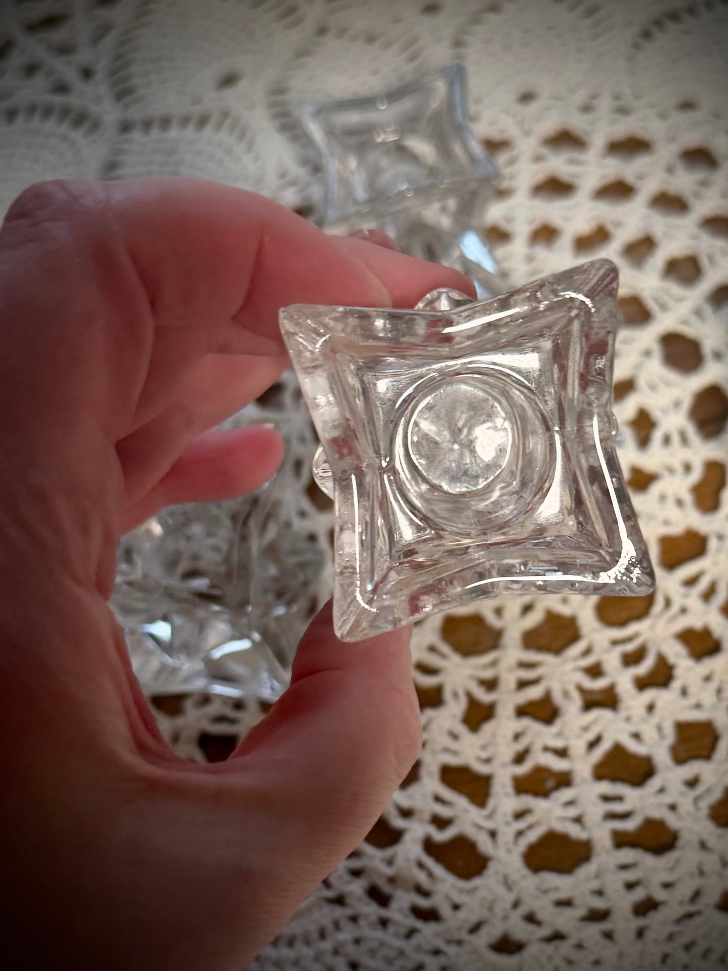 A hand holding a small glass geometric candle holder