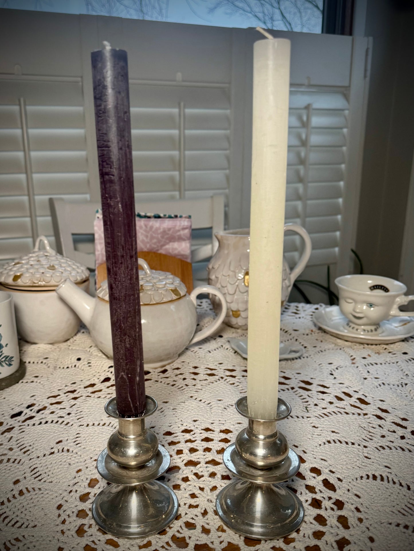 Two small pewter candlesticks holding a black and a white taper candle