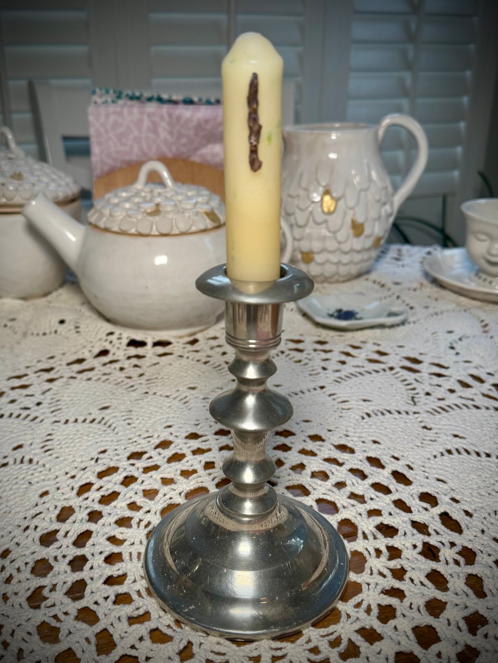 A pewter candlestick with a small white taper candle