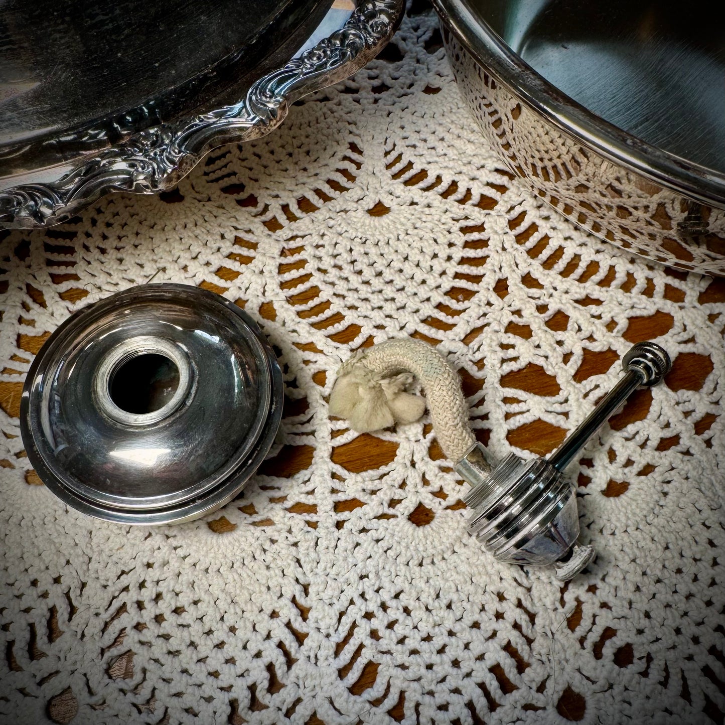 Vintage oil burner shown in two pieces with wick exposed on a white lace tablecloth