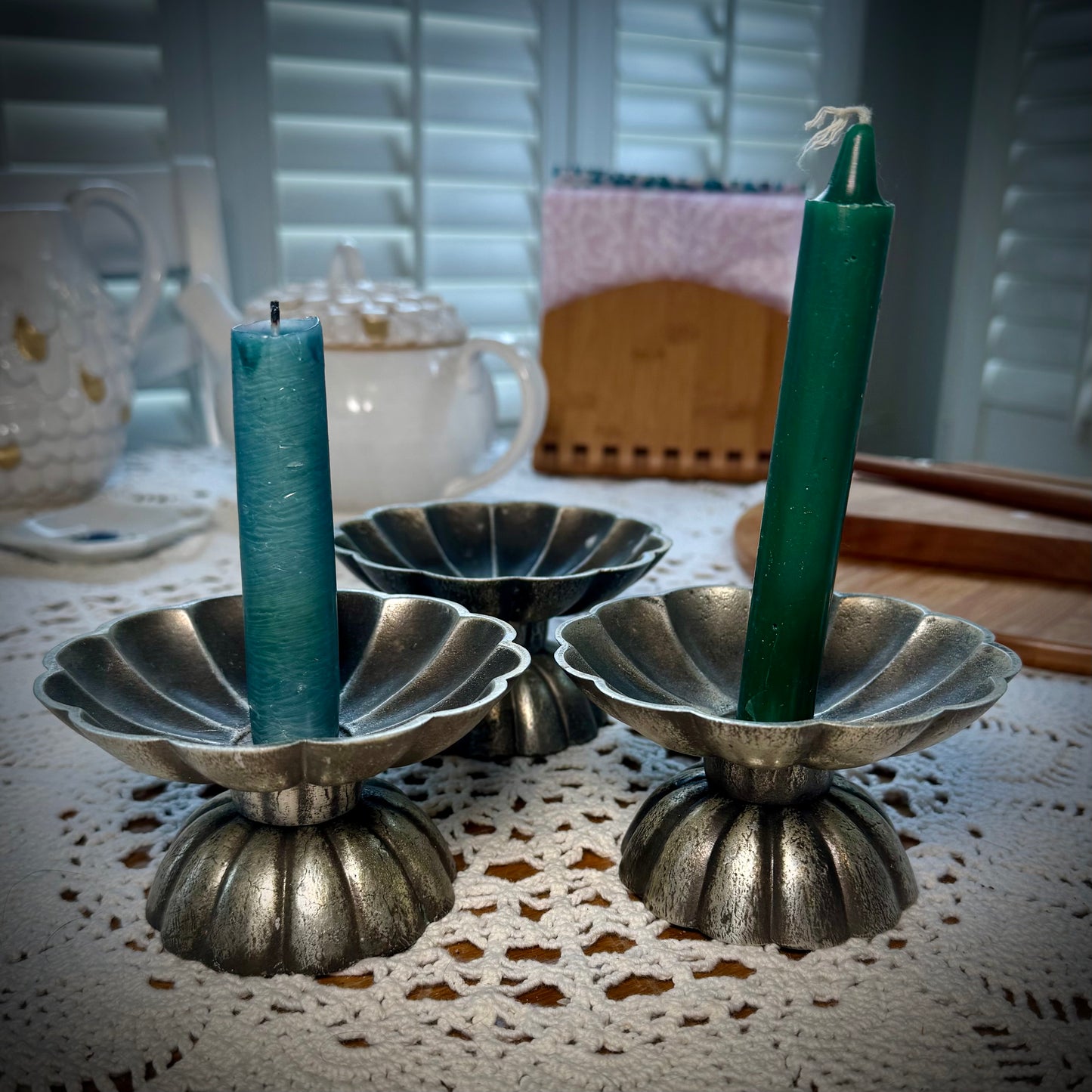 Three vintage pewter swirled taper candle holders, two holding thing pillar candles.