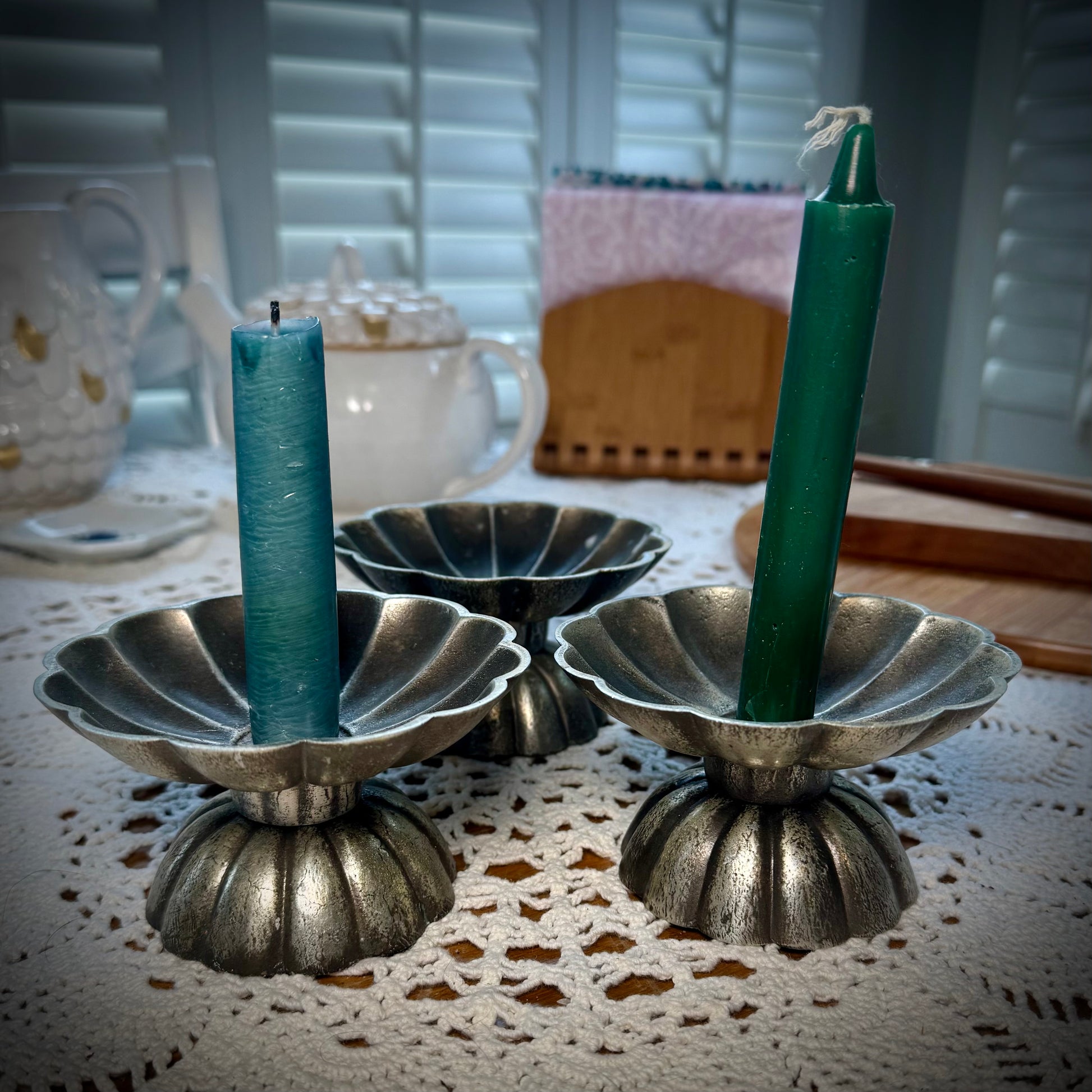 Three vintage pewter swirled taper candle holders, two holding thing pillar candles.