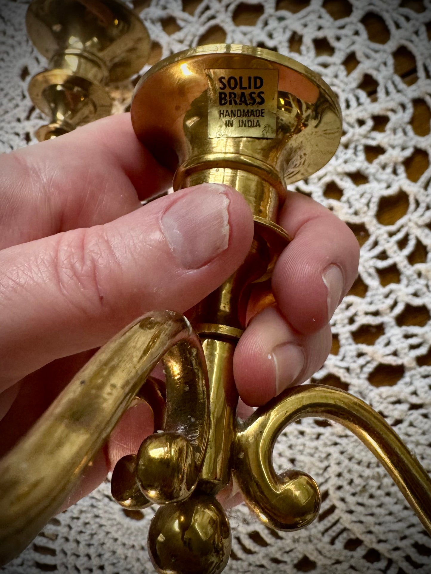 A close up of the bass of a brass candleabra with the words "Solid Brass"