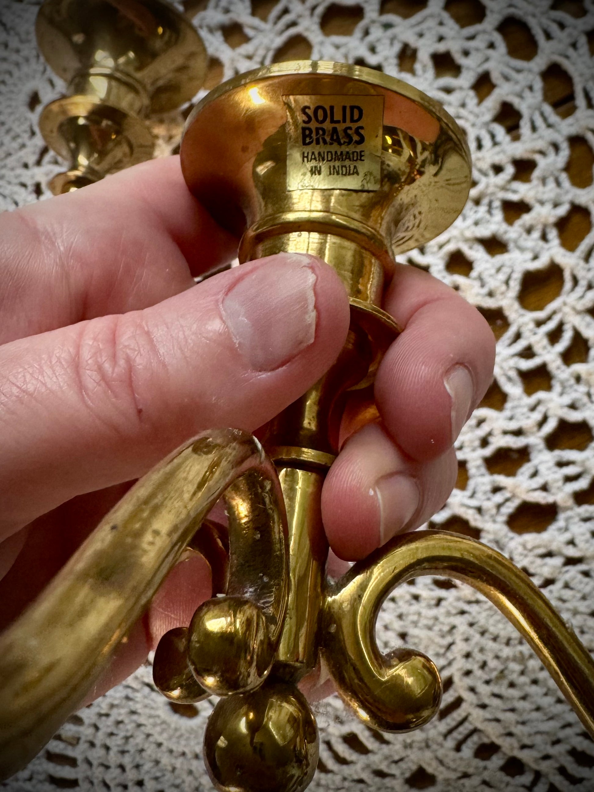 A close up of the bass of a brass candleabra with the words "Solid Brass"