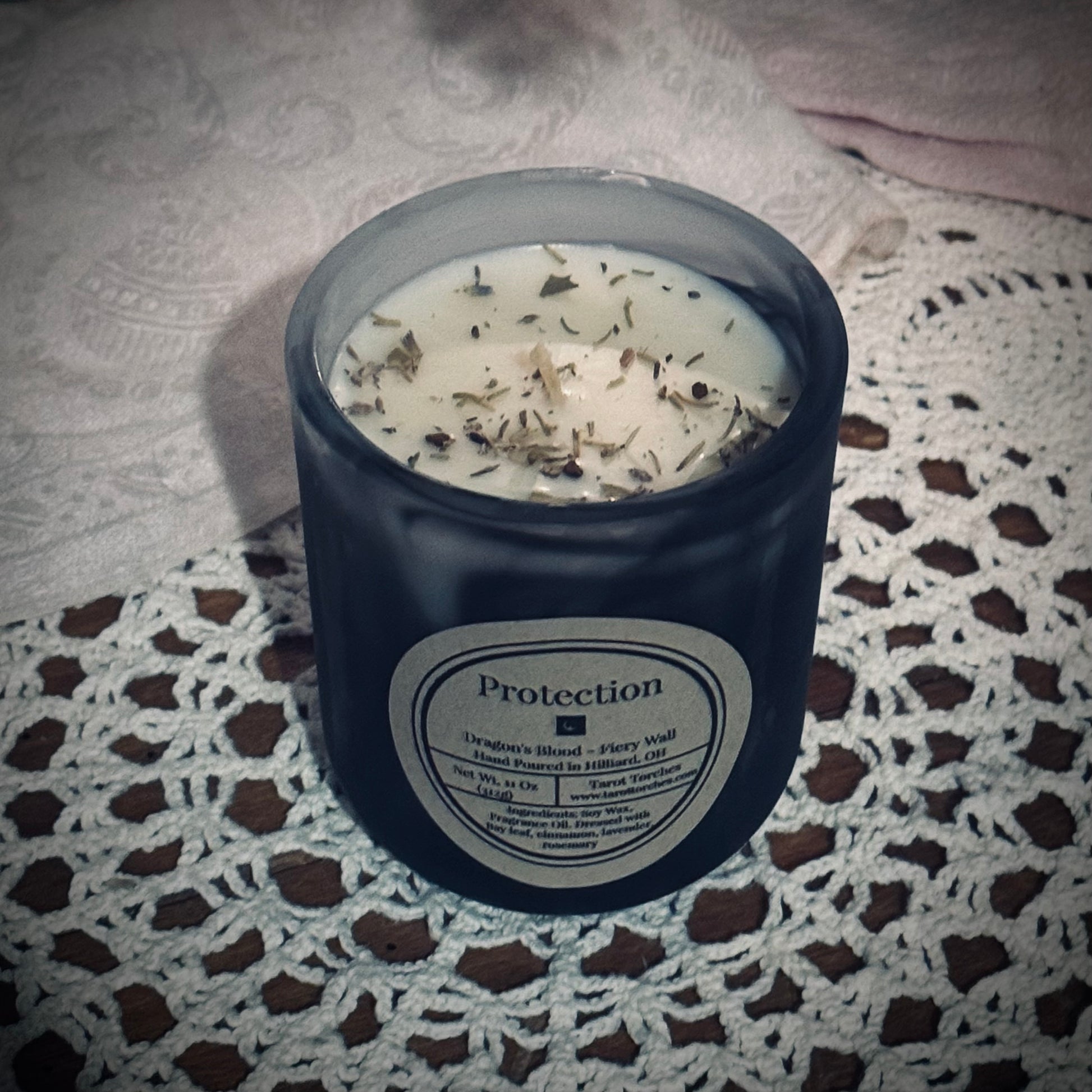 A soy wax candle with a black swirl vessel, with a label that reads "Protection".