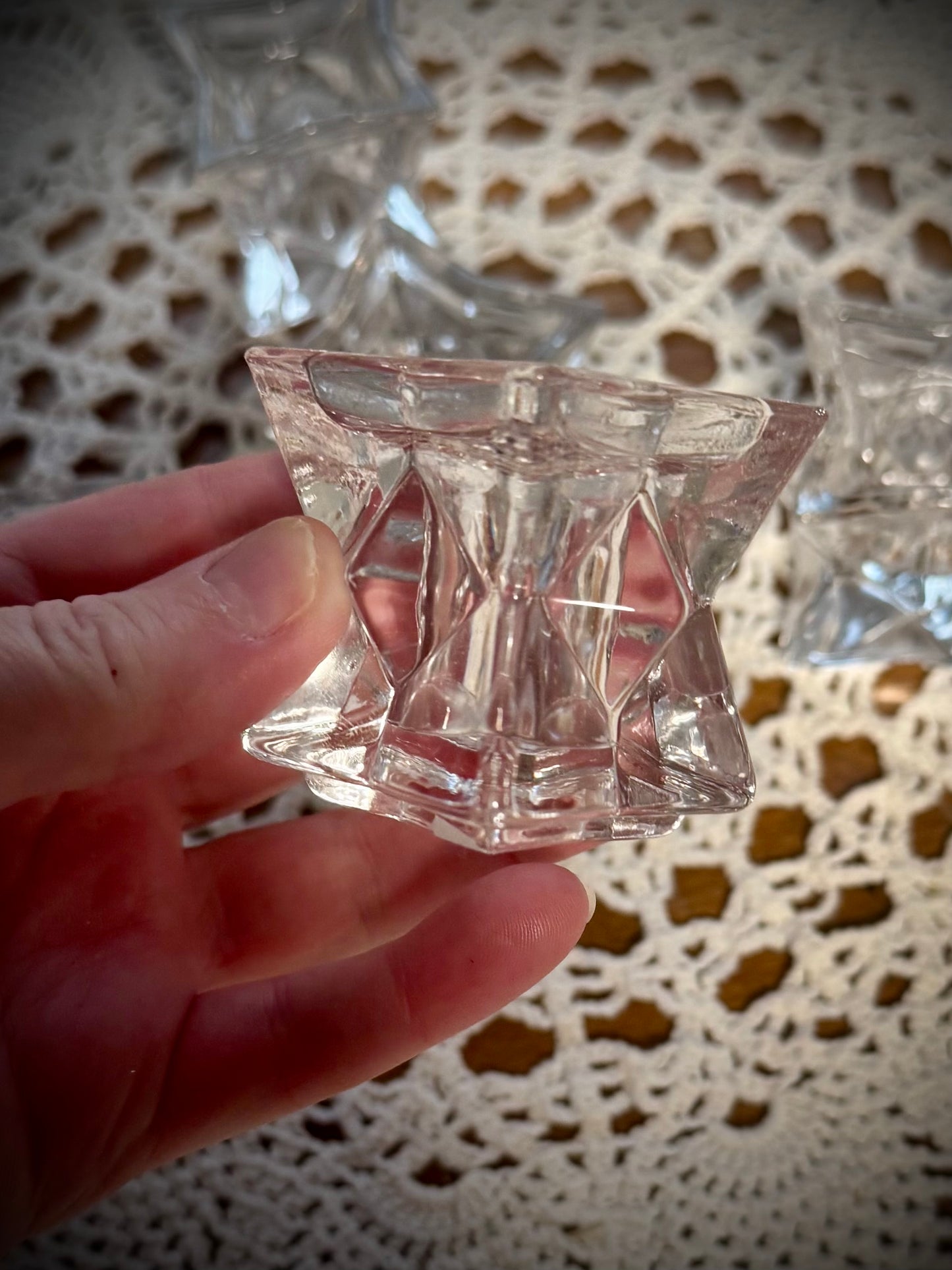 A hand holding a small glass geometric candle holder
