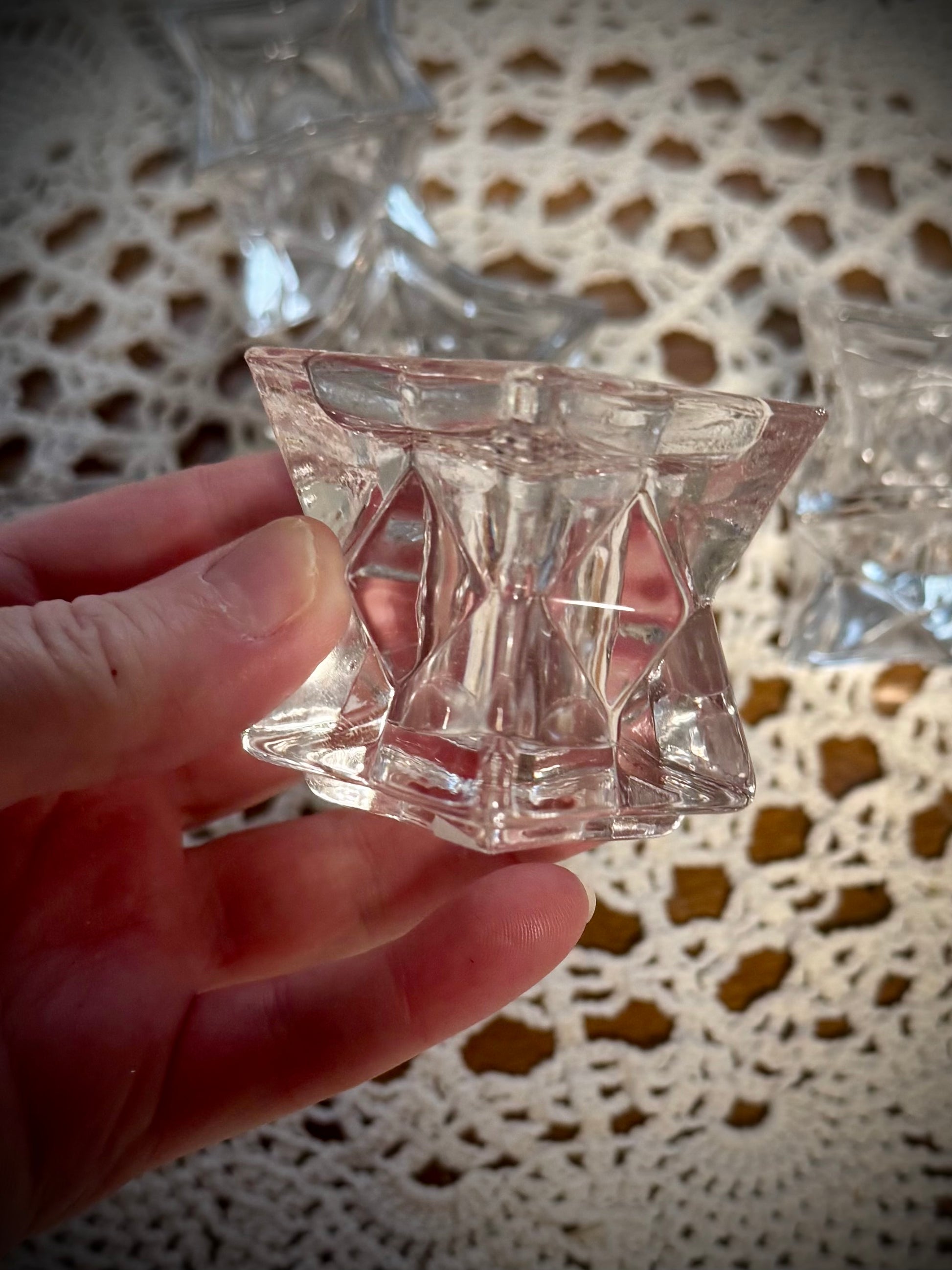 A hand holding a small glass geometric candle holder