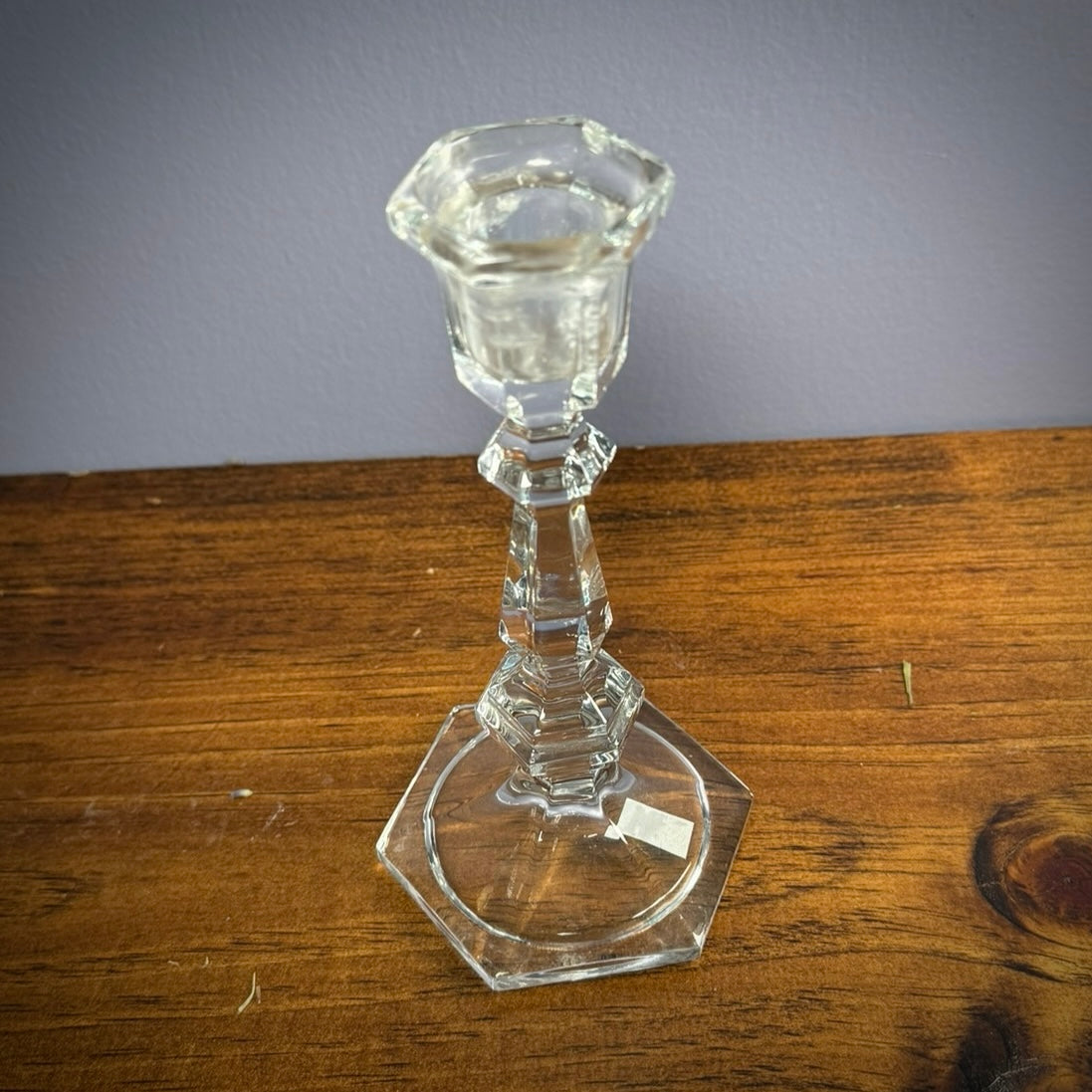 Vintage glass candlestick sitting on a wooden surface.