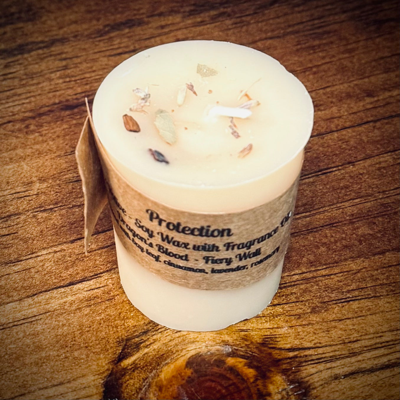 A white votive candle with natural soy wax  labeled 'Protection' placed on a wooden surface.