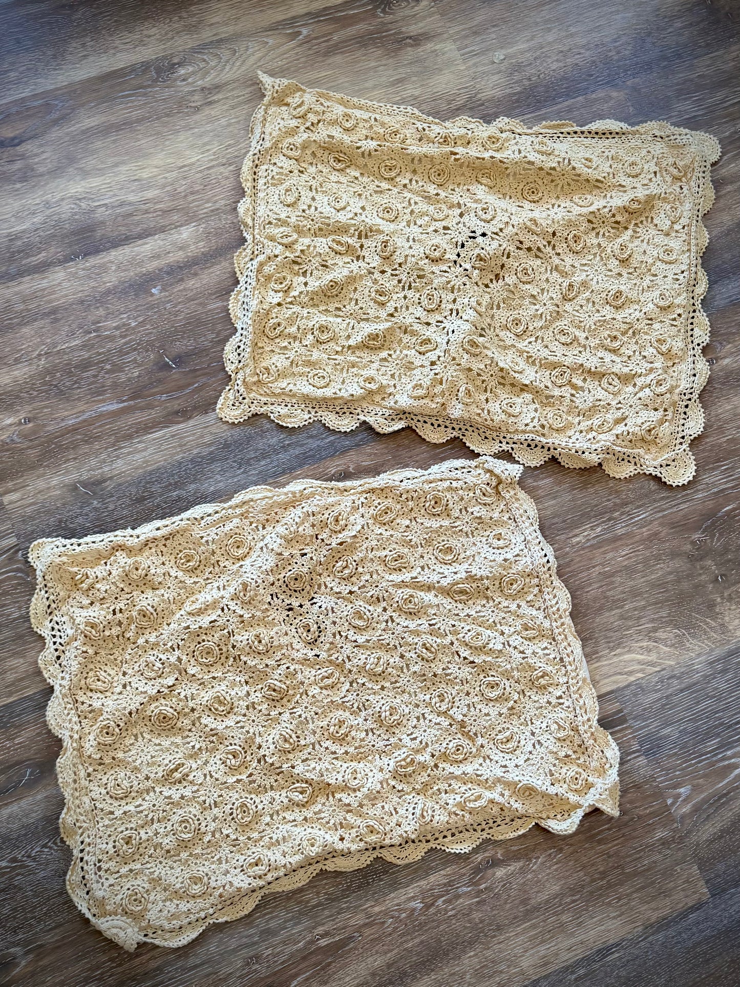 Two beige pillowcases featuring a floral rosette pattern and a scalloped edge.
