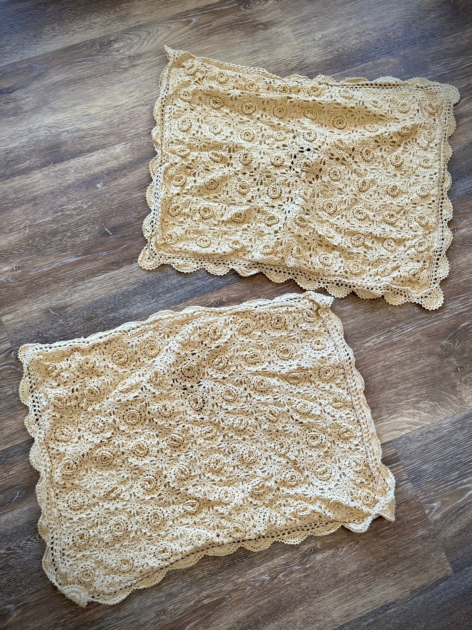 Two beige pillowcases featuring a floral rosette pattern and a scalloped edge.