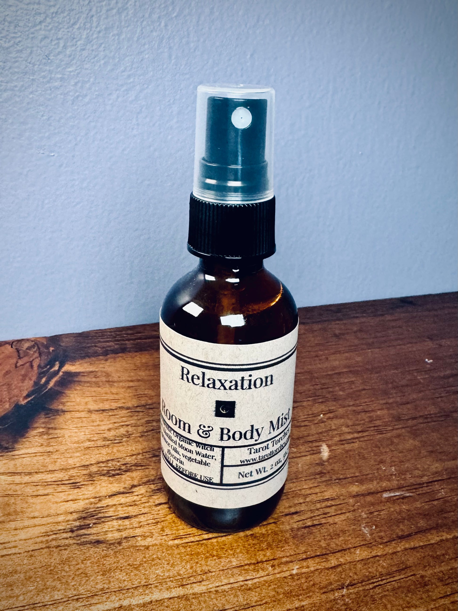 An amber glass spray bottle with a label reading "Relaxation" on a wooden surface.