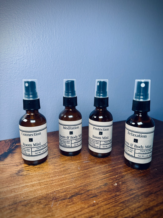 A set of four amber glass spray bottles with kraft labels on a wooden surface.