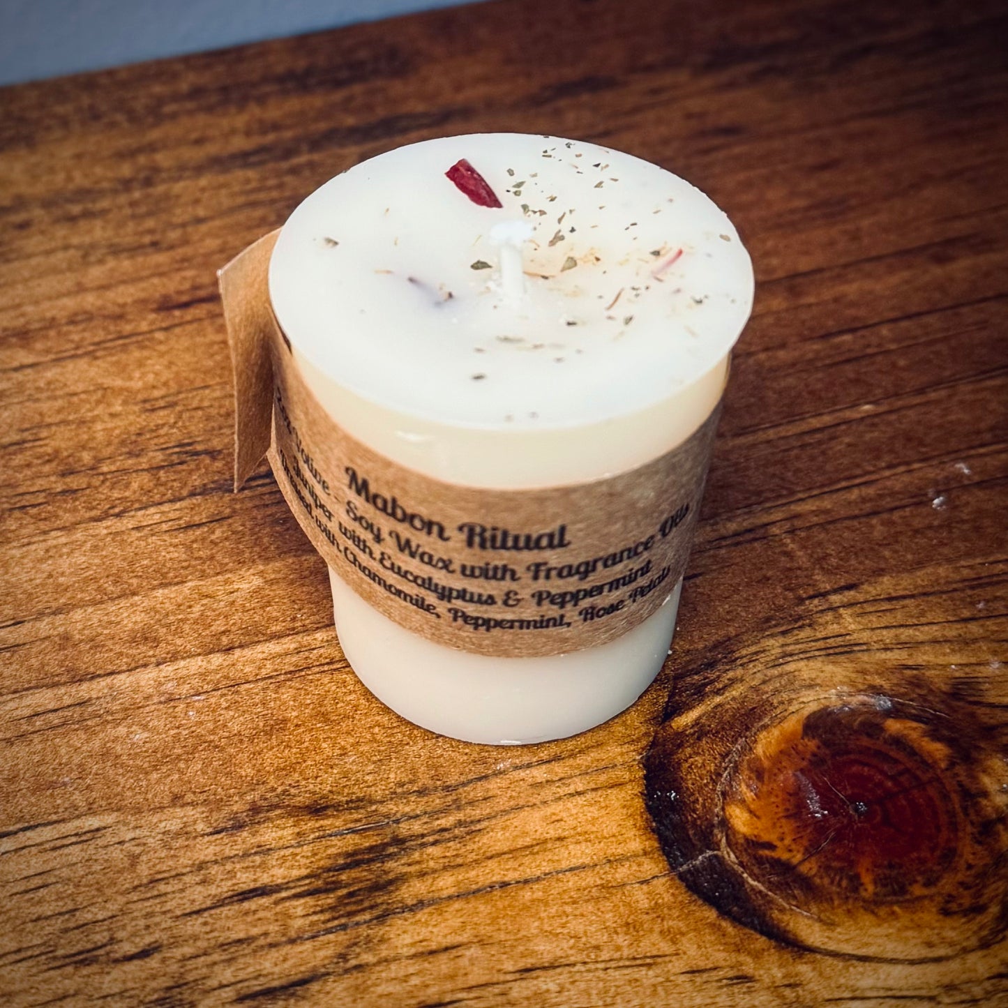 A white votive candle with a label reading "Mabon Ritual" on a wooden surface.