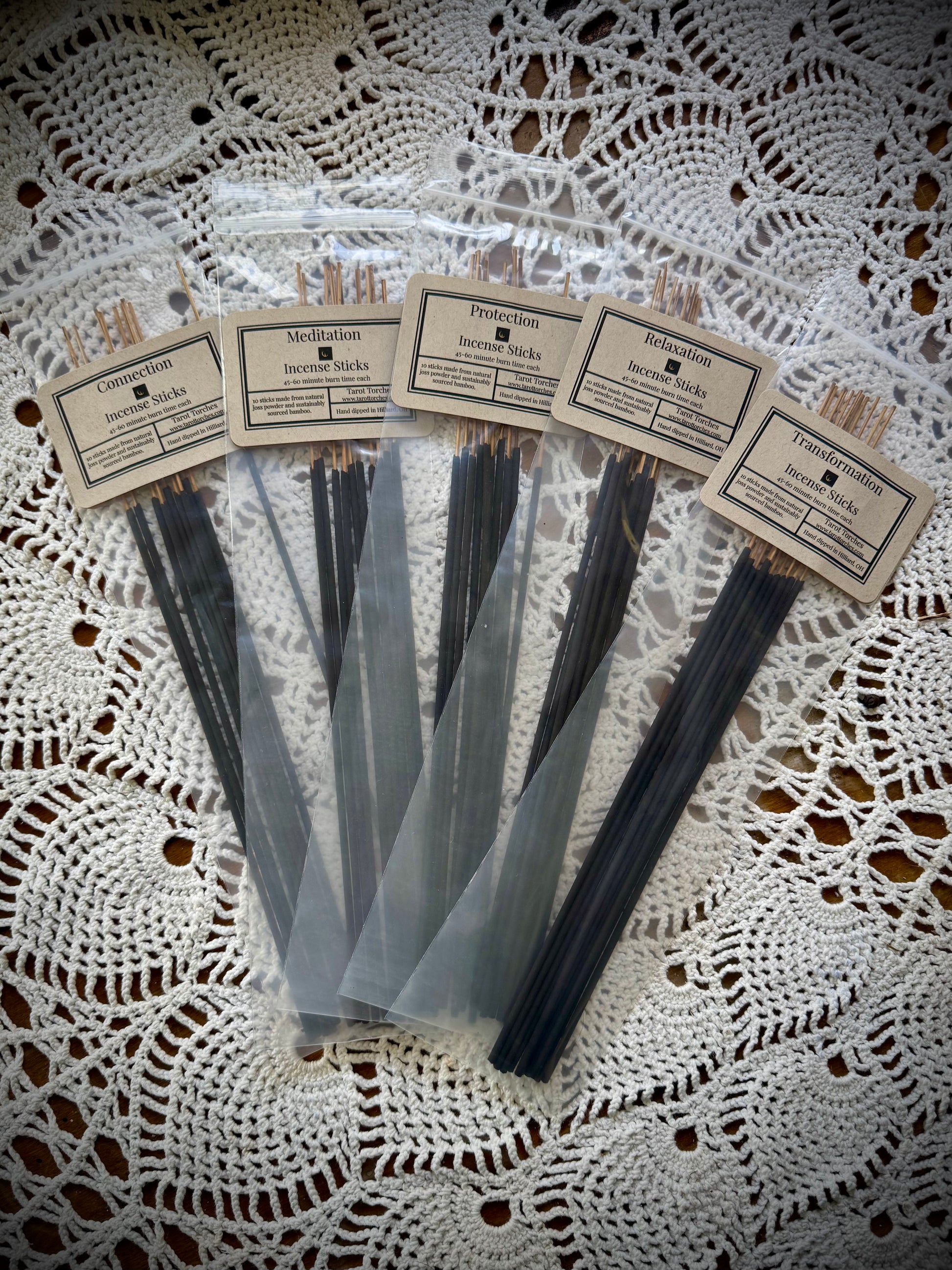A pack of incense sticks with labels, displayed on a lace background.