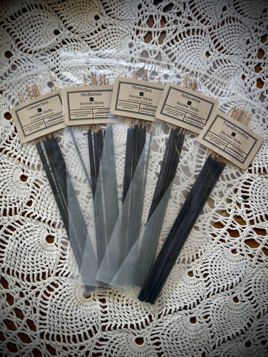 A pack of incense sticks with labels, displayed on a lace background.