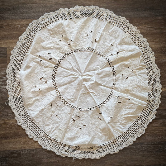 A 31-inch round vintage crochet altar cloth with slight discoloration, displayed on a wooden surface.