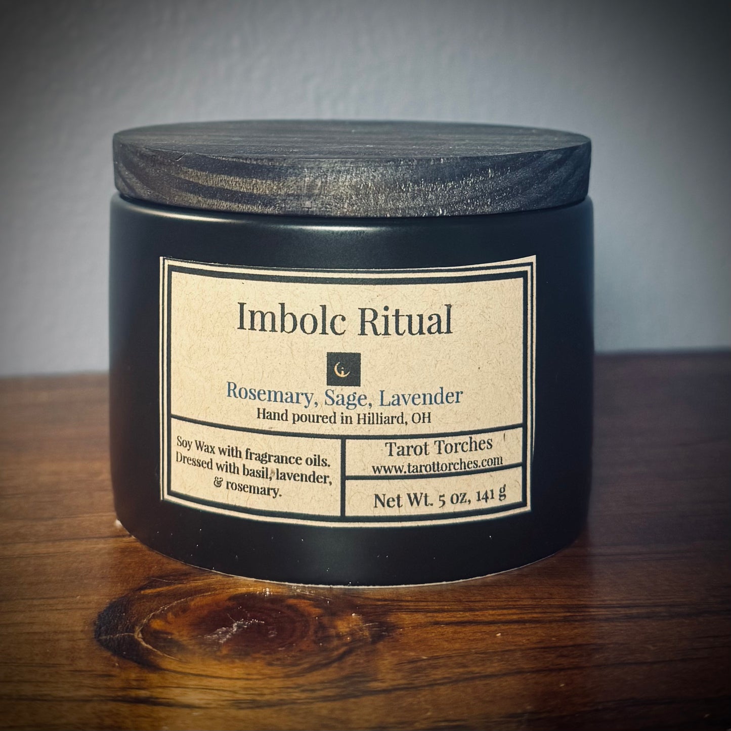 A black jar candle with a black lid and label reading "Imbolc Ritual"