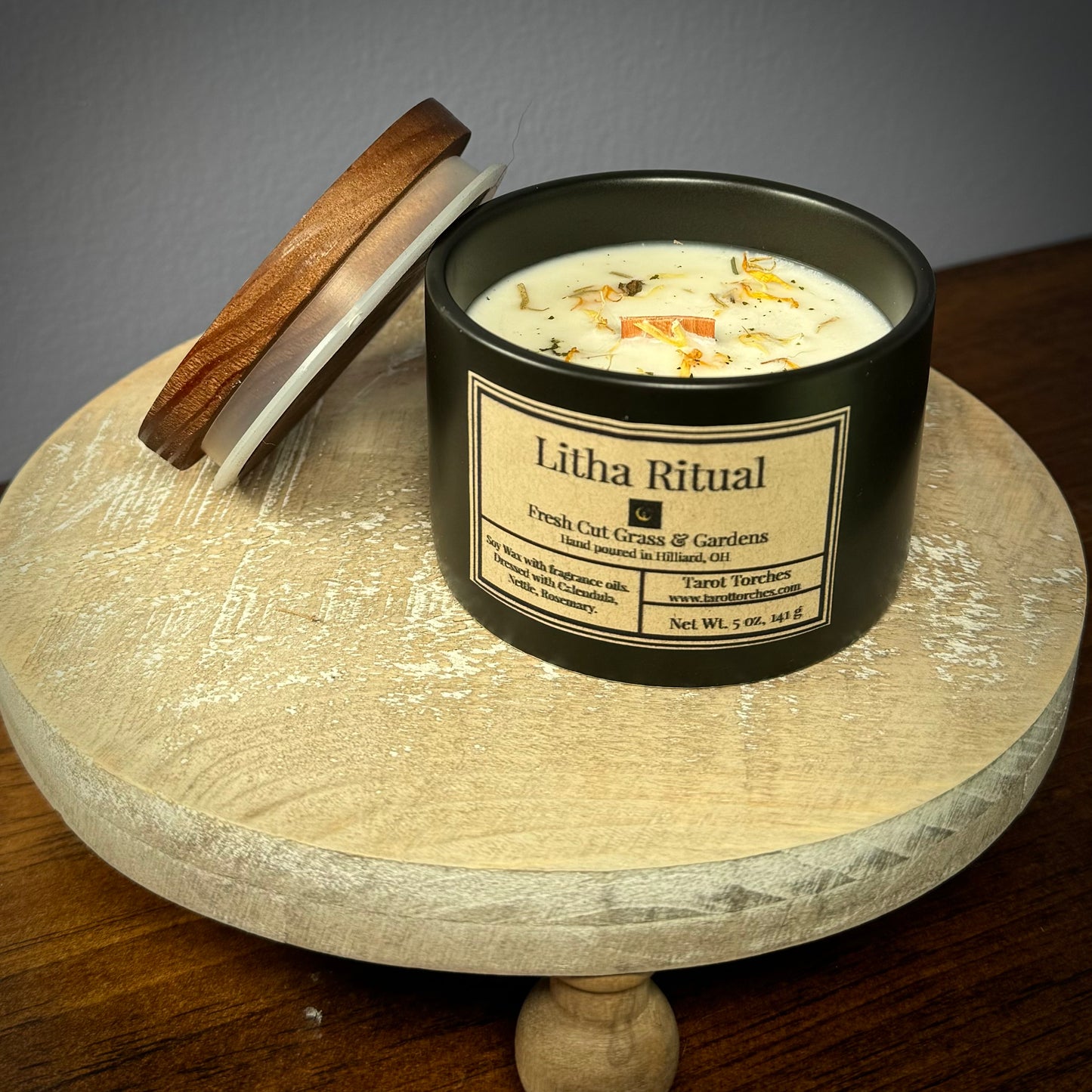 Candle labeled 'Litha Ritual' with an offset pine lid on a wooden surface