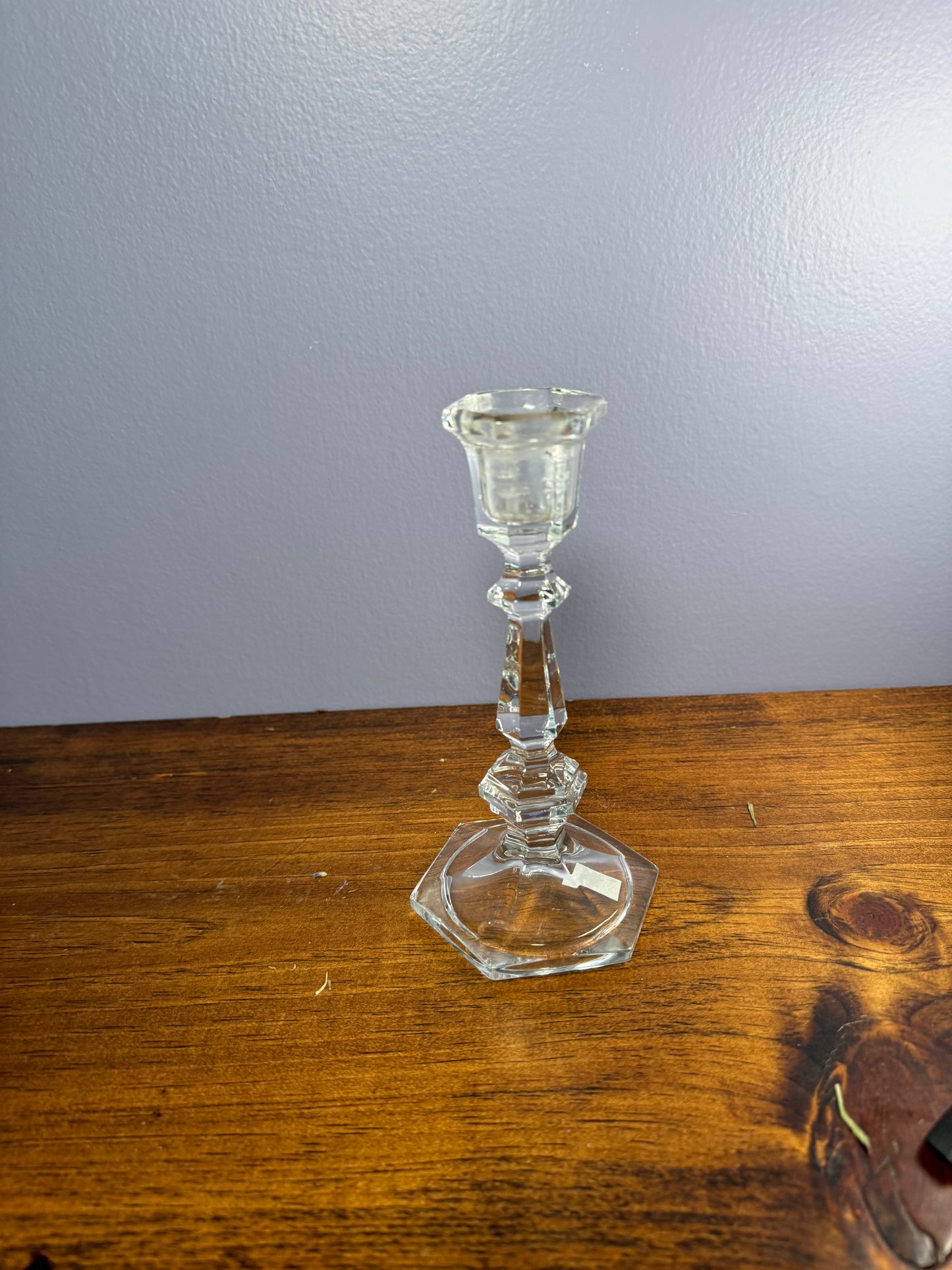 Vintage glass candlestick sitting on a wooden surface.