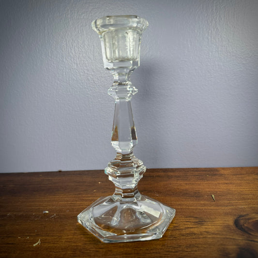 Vintage glass candlestick sitting on a wooden surface.